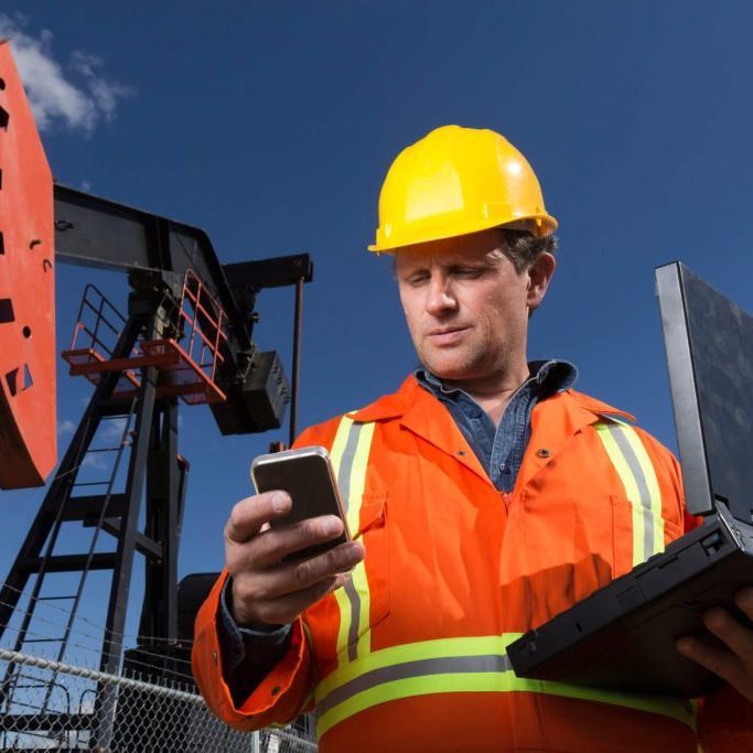 engineer working on a construction site with a laptop and a smartphone
